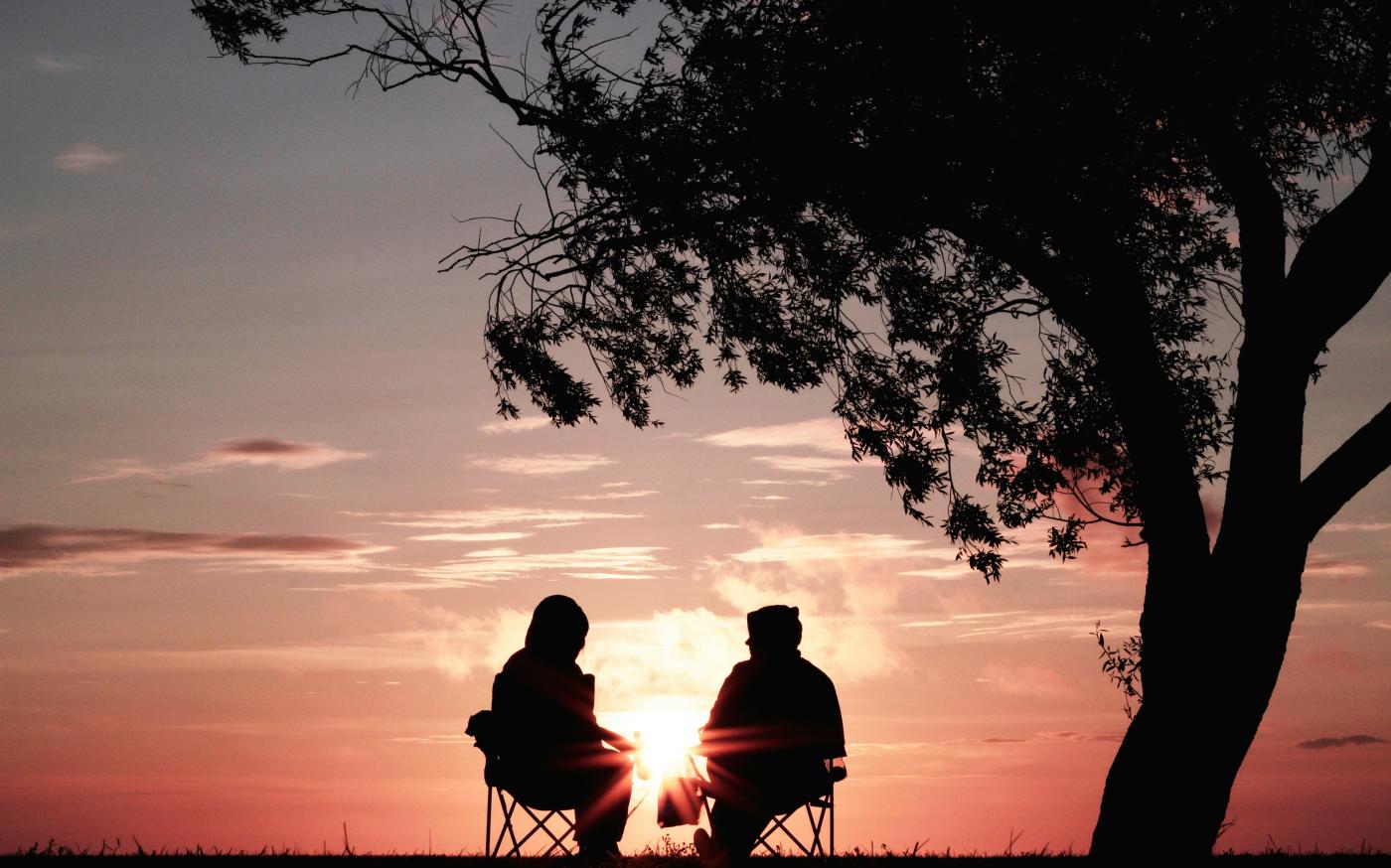 silhouette of two person sitting on chair near tree by Harli  Marten courtesy of Unsplash.