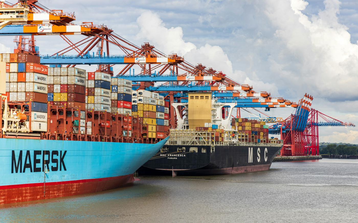 blue and red cargo ship on dock during daytime by Dominik Lückmann courtesy of Unsplash.